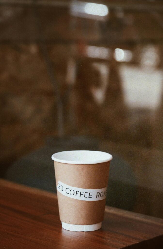 A brown coffee cup sits elegantly on a wooden table in a cozy cafe setting.